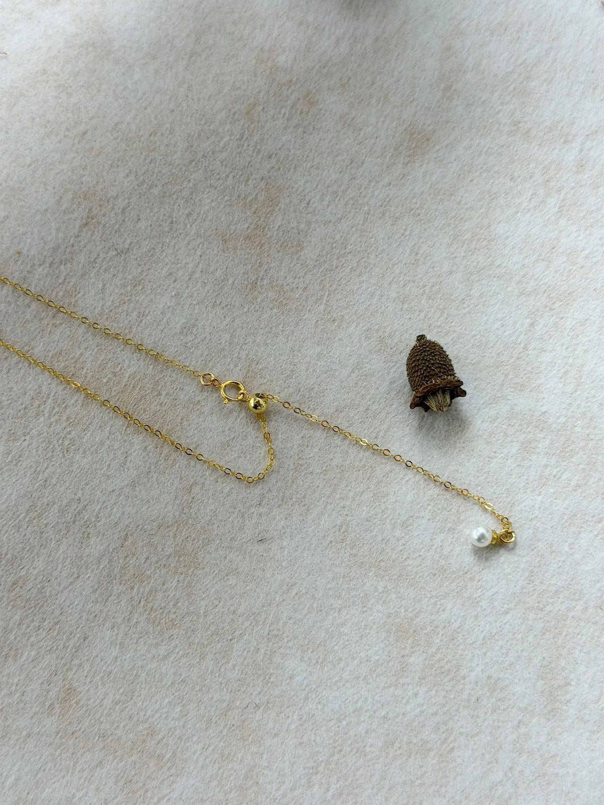 Detailed view of 14K gold-filled silicone slider bead mechanism with mini pearl tail.