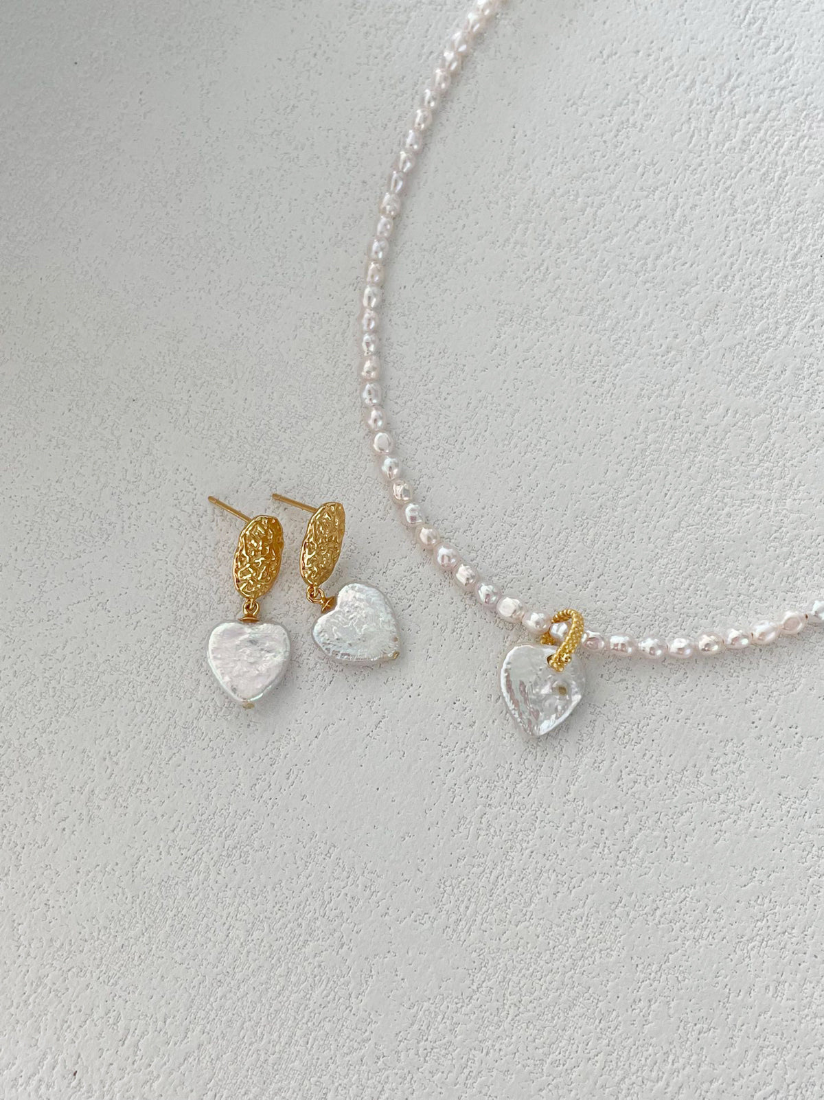 Romantic pale pink heart pearl necklace on neutral backdrop, feminine bridal pearl accessory