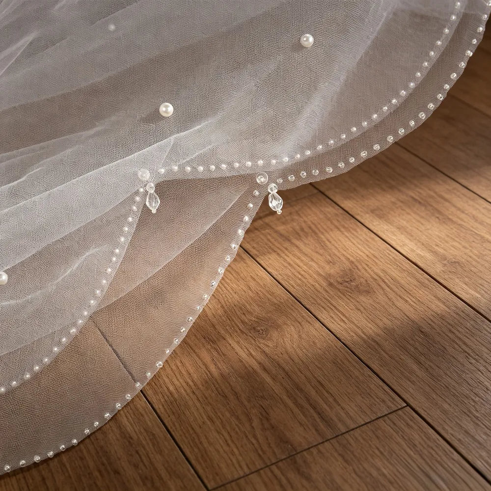 Detailed view showing continuous seed bead border and spaced crystal drops curving along soft tulle mesh