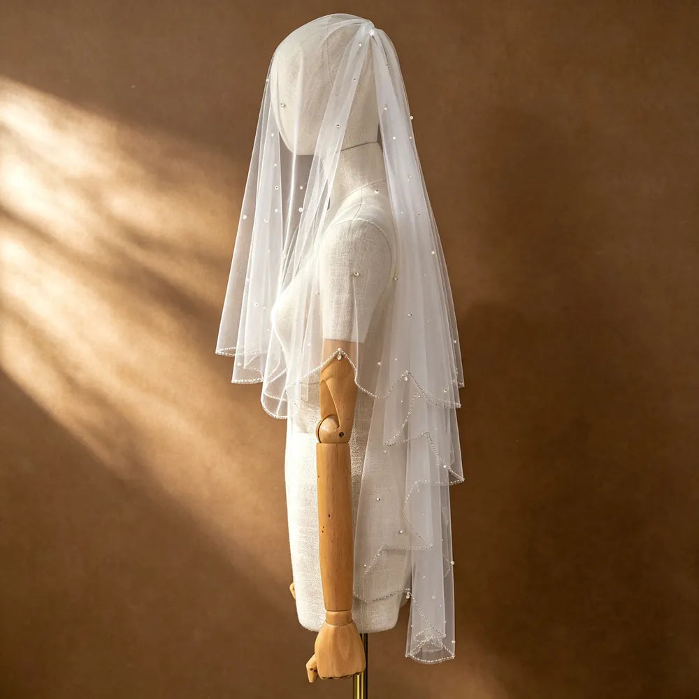 Rear three-quarter angle of bride showcasing 2-tier veil drape over off-the-shoulder lace corset gown