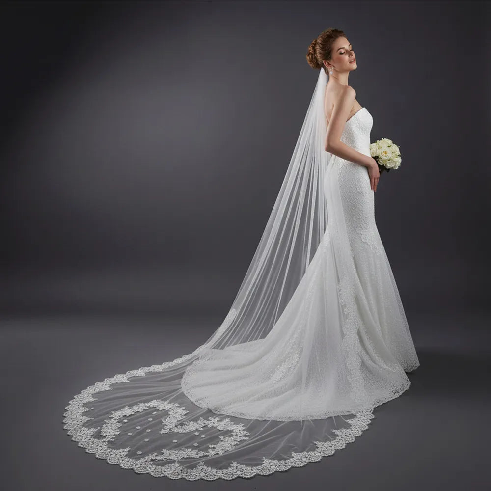 Side view of bride in fitted white dress showcasing 300cm lace train spreading in a smooth arc across grey studio floor