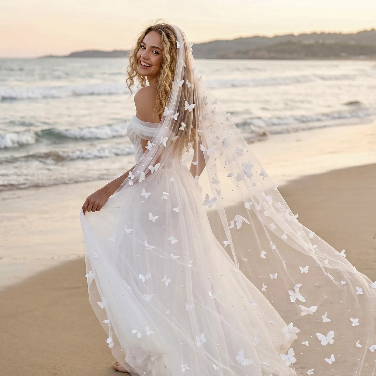 Happy bride on sandy beach showing trailing 3D butterfly veil flowing in the seaside breeze
