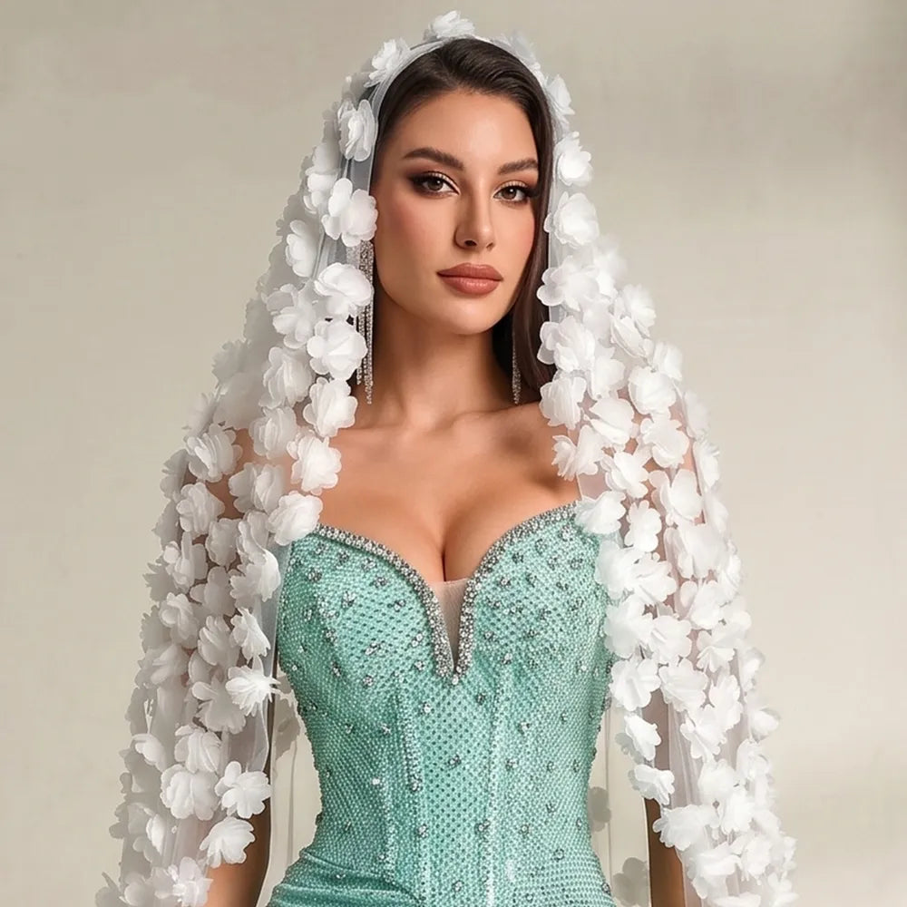 High-resolution detail of layered white chiffon fabric flowers stitched along tulle border