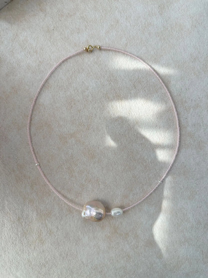 Studio shot of 40-41cm fairy pink baroque pearl necklace laid flat on soft fabric.