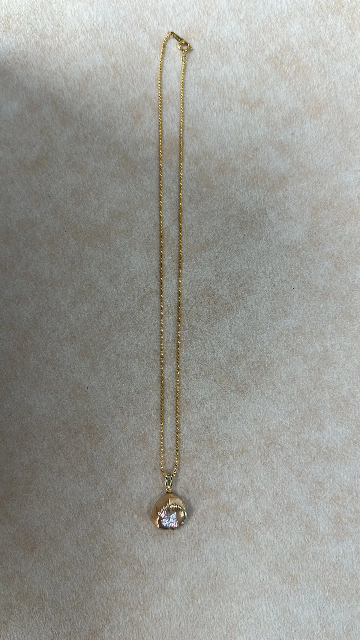 Full view flatlay of the 41cm gold beaded chain with petal pearl pendant.