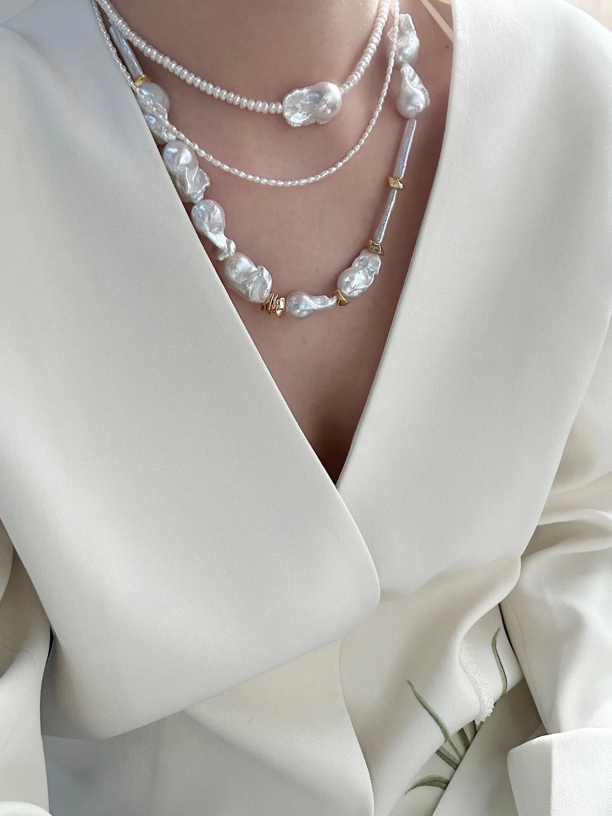 Model styling the 45cm barn-style baroque pearl necklace layered with a shorter chain under a white blazer.