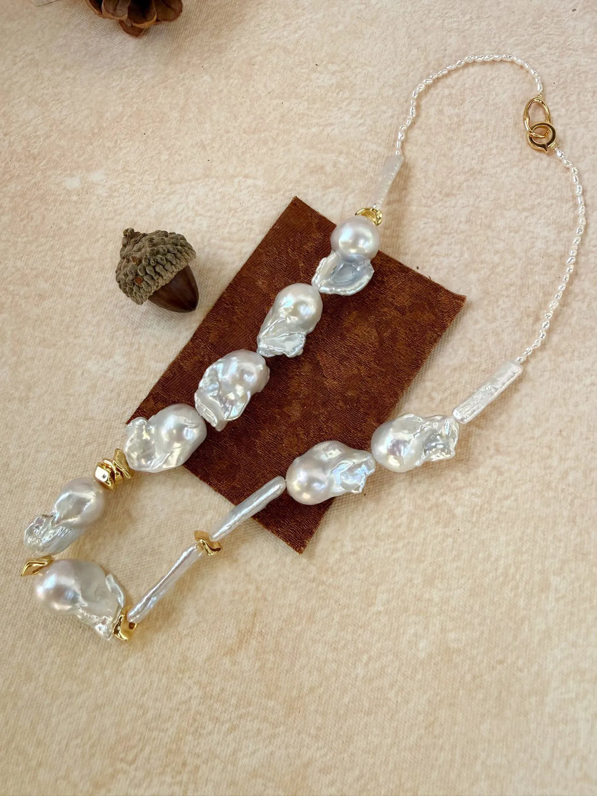 Detailed close-up of the 925 sterling silver 18k gold-plated lobster clasp and seed pearl backing.