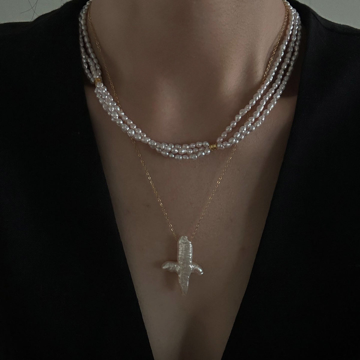 A delicate three-strand pearl necklace worn with a wedding dress, creating a soft and elegant bridal look.
