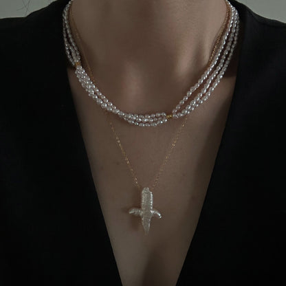A delicate three-strand pearl necklace worn with a wedding dress, creating a soft and elegant bridal look.