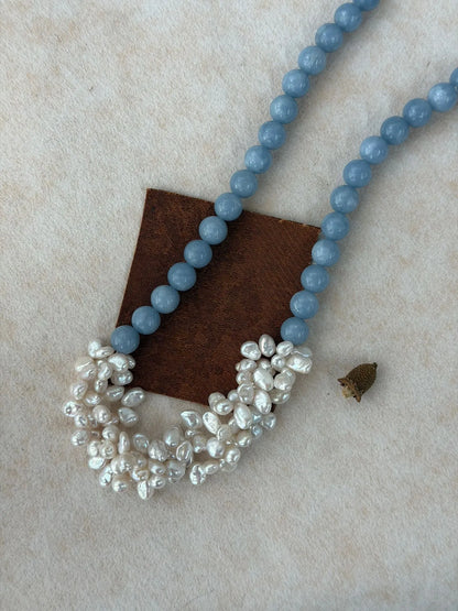 Angelite bead strand and woven pearl cluster necklace displayed with a brown leather prop accent.   