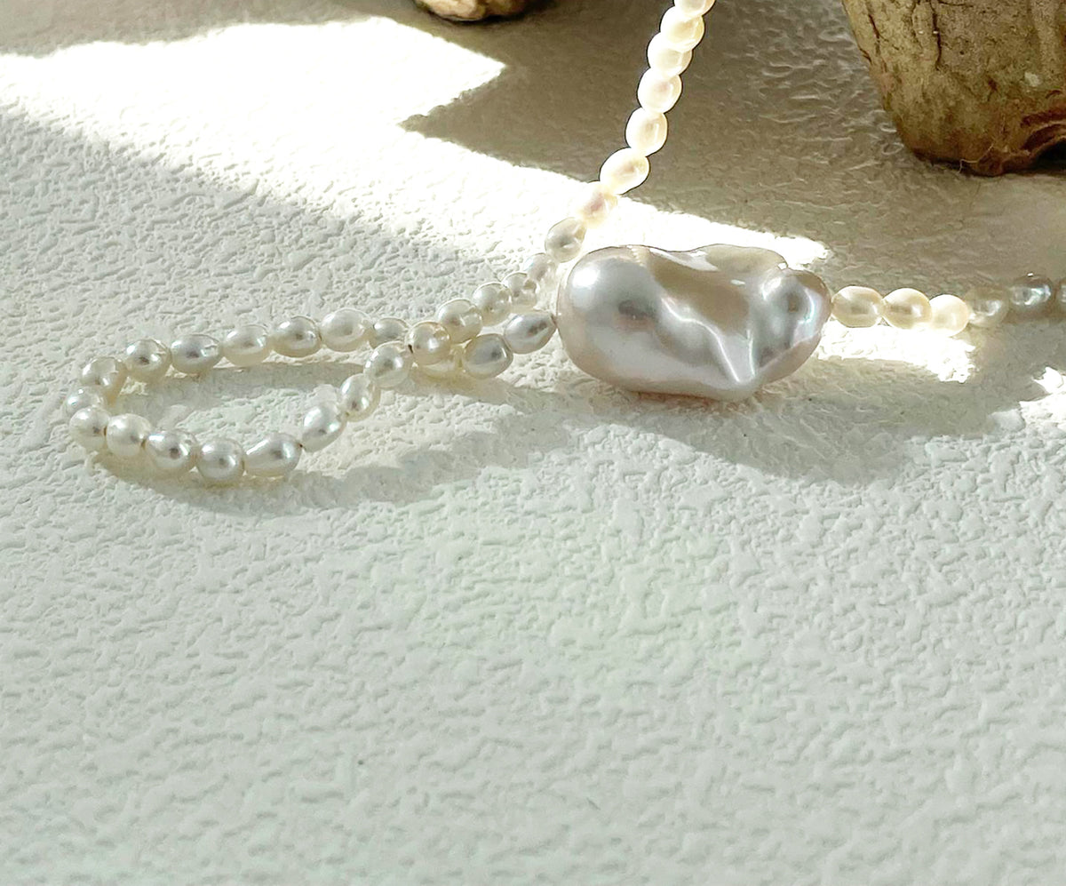 Close-up of the irregular baroque pearl and delicate pearl strand