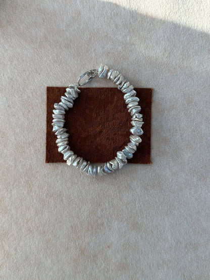 Single strand baroque freshwater pearl bracelet with S925 silver clasp on brown fabric display.