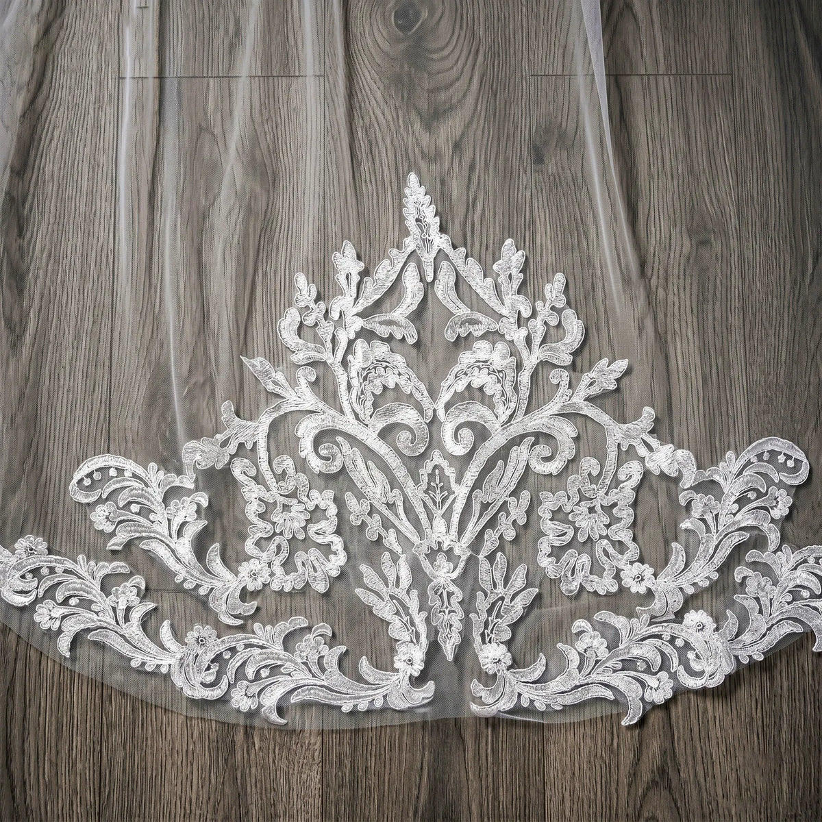 Detailed close-up of intricate Renaissance baroque scroll lace appliqué stitched onto sheer tulle