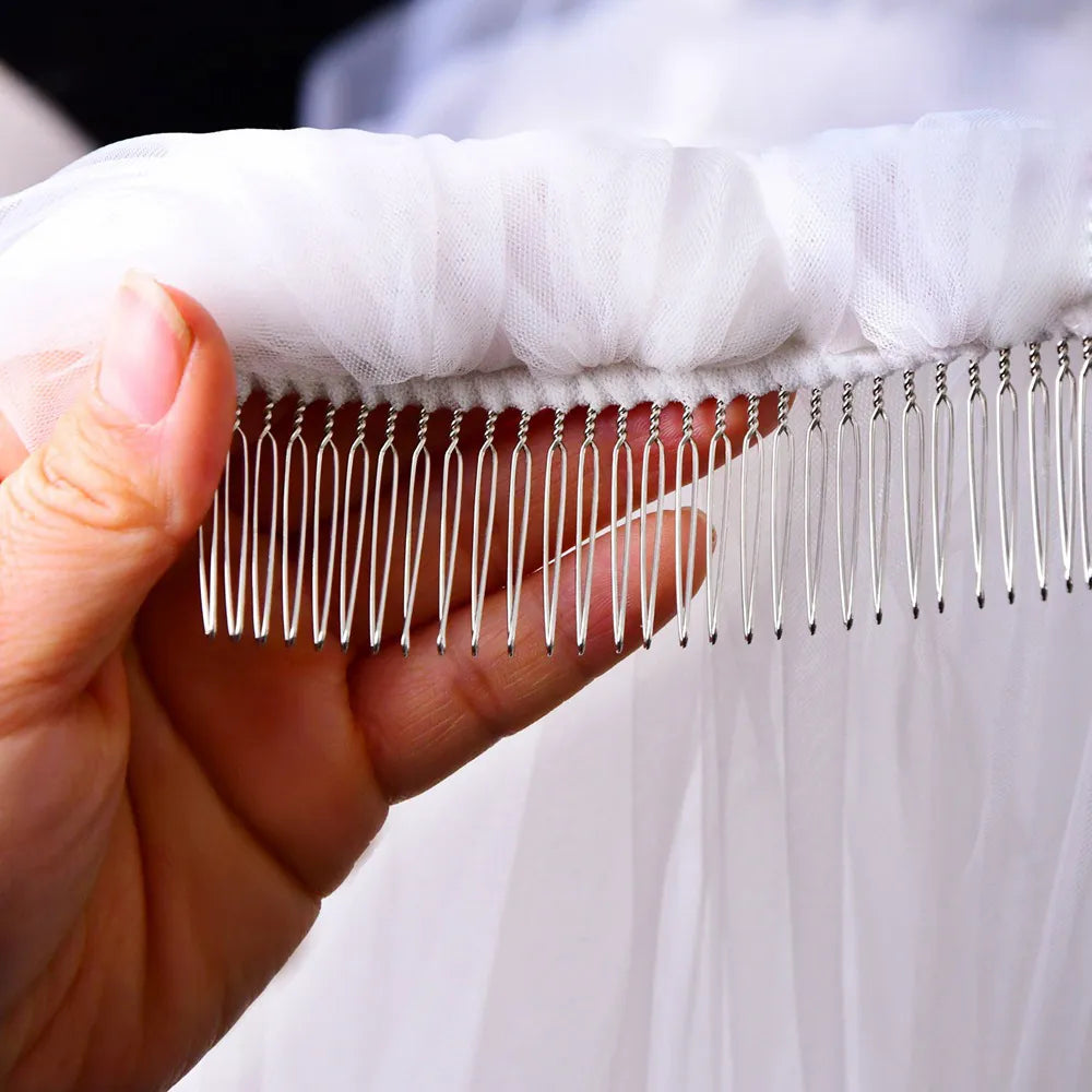 Hand holding pre-attached silver metal hair comb stitched into gathered tulle headpiece
