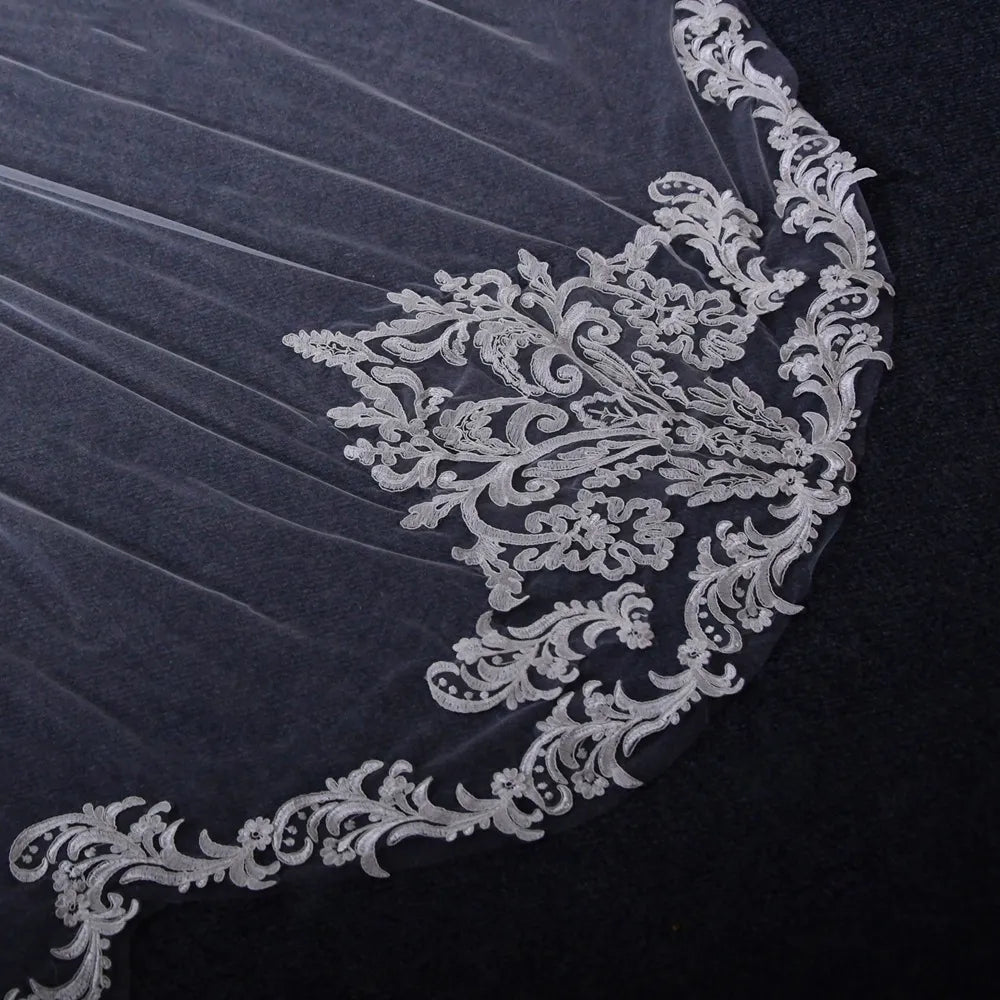 Close-up of baroque crest lace motif and embroidered scalloped edge displayed on dark background