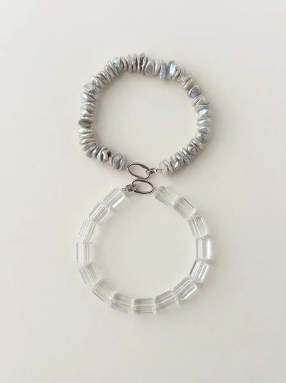 Figure-eight layout of baroque pearl and clear quartz crystal strands with sterling silver closures.
