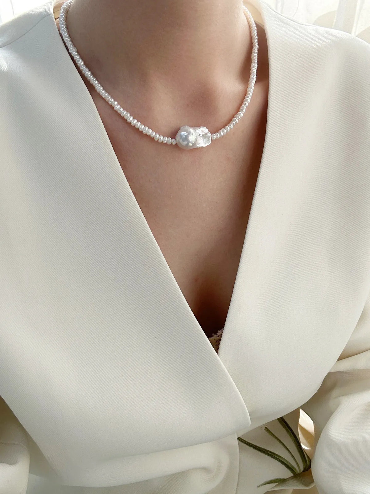 Model wearing the single baroque pearl seed bead choker with a white deep V-neck top.