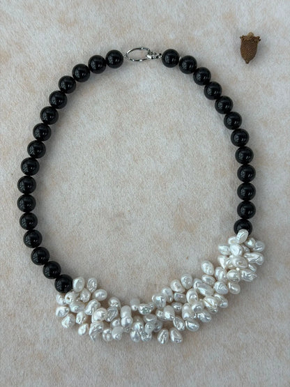 Top-down flatlay of black agate strand seamlessly woven into a statement white pearl petal cluster.