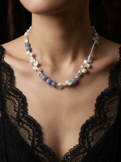 Model wearing blue gemstone and freshwater petal pearl necklace with a black lace dress