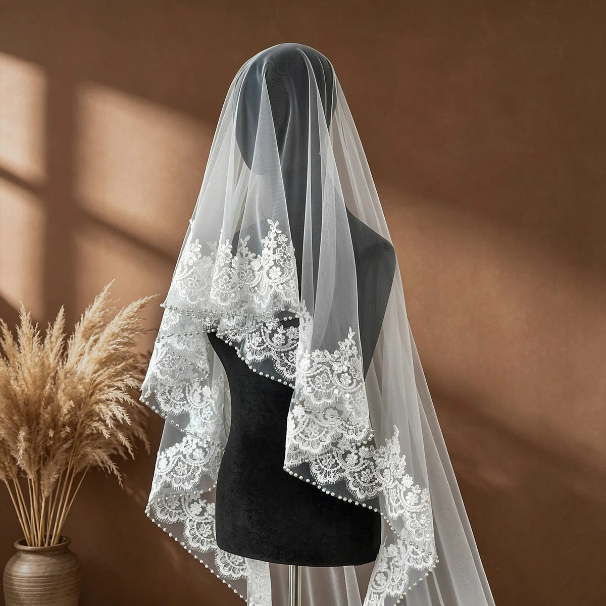 Three-quarter angle view of veil on mannequin showing rich lace border and fluid cascading tulle falling to the wooden floor
