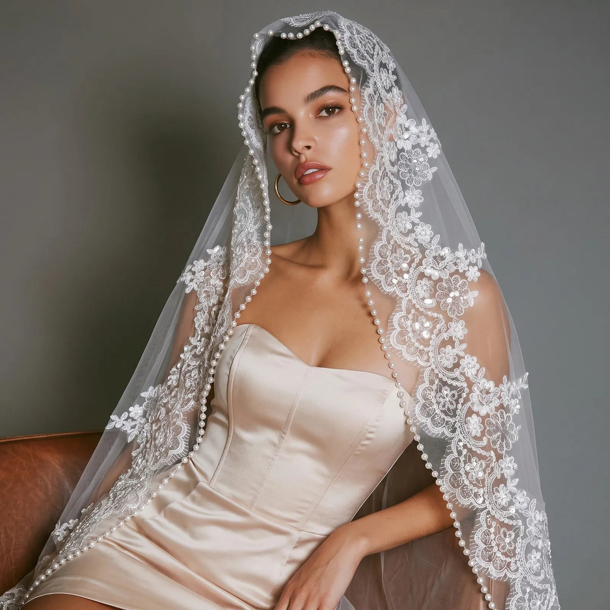 Front close-up view of bride with sheer veil over face, showcasing intricate floral lace appliques and dangling pearl beaded border