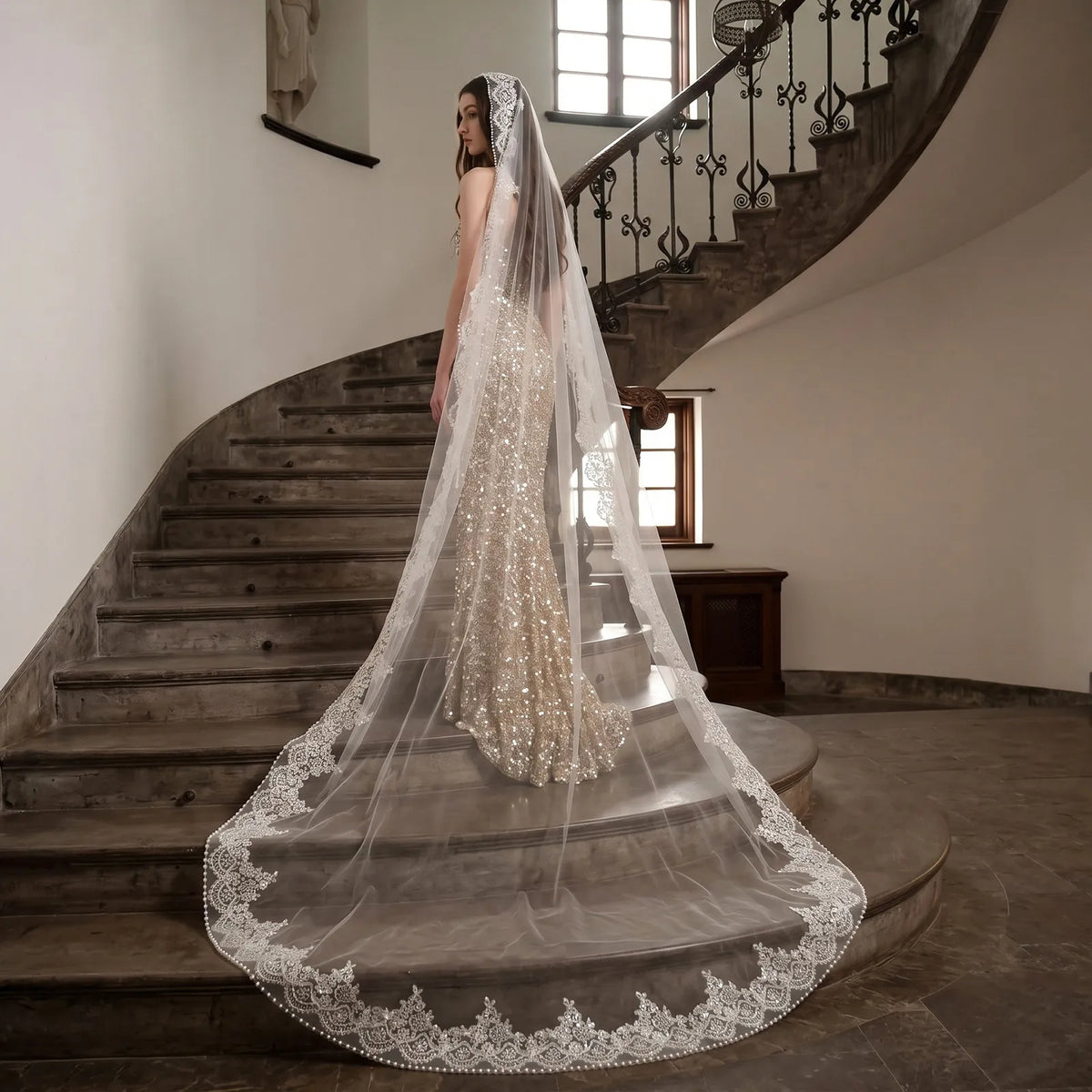 Elegant side view of bride standing with cathedral veil flowing smoothly down her gown, highlighting light reflection on sequins and pearls