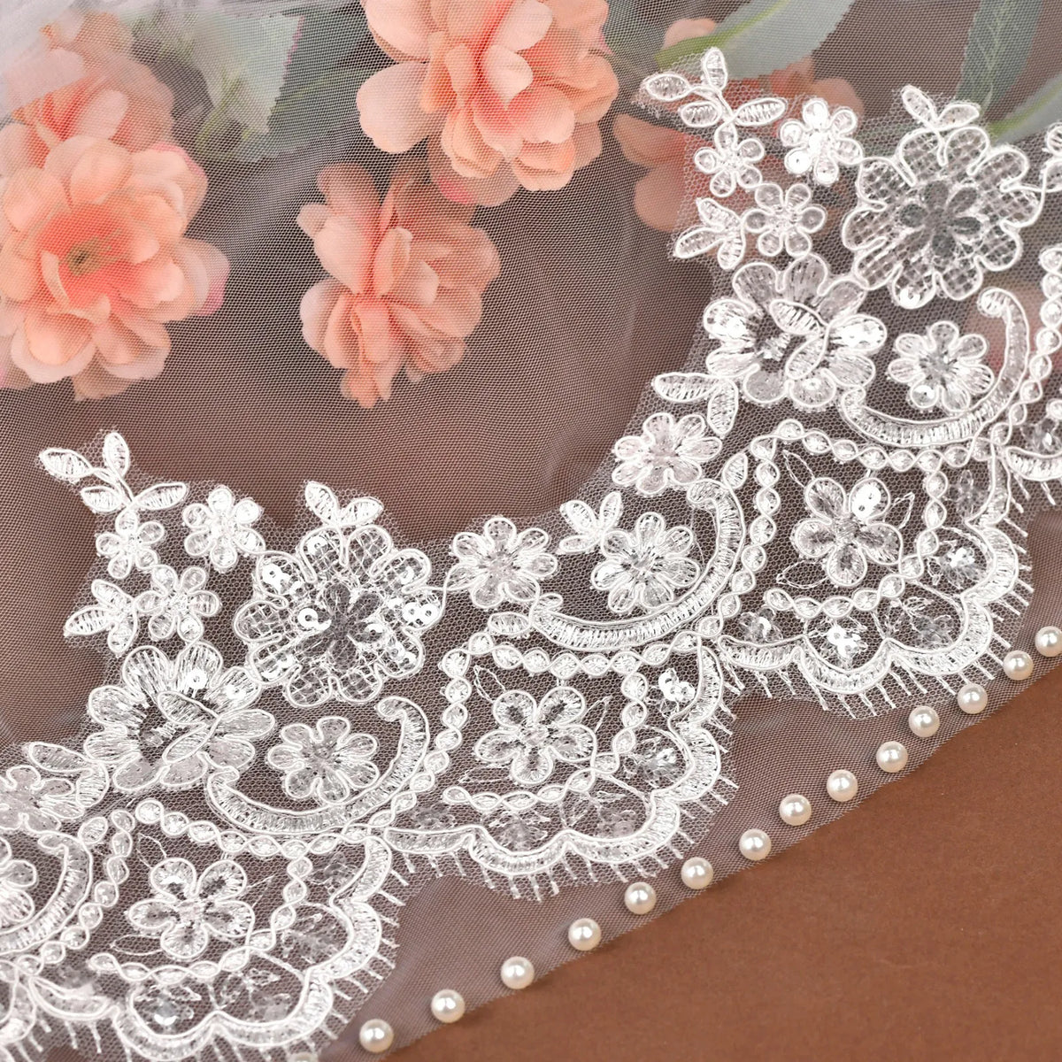Macro view of floral embroidered lace pattern with clear sequin accents and delicate white faux pearl trim laid over flowers
