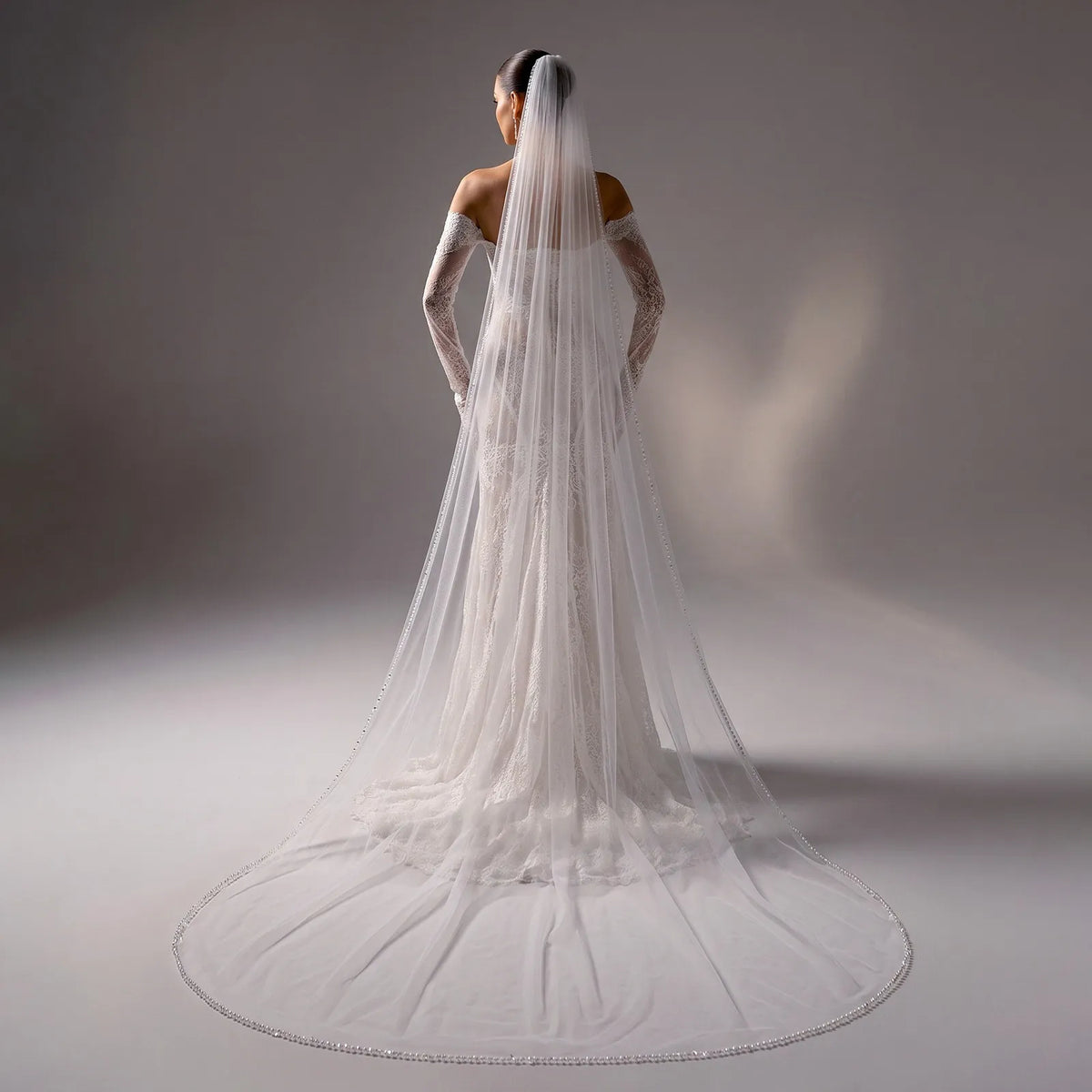 Rear view of bride in strapless lace gown wearing a 300cm single-tier veil with delicate pearl trim cascading into a wide-spread circular train