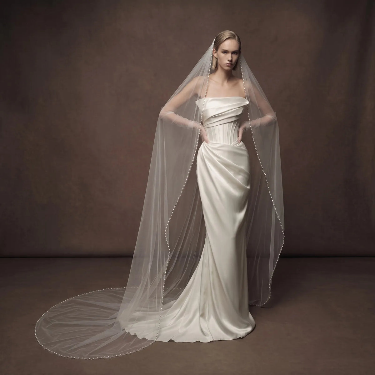 Full-length portrait of bride in fitted strapless gown with cathedral length veil cascading to the floor and forming a wide semi-circle train