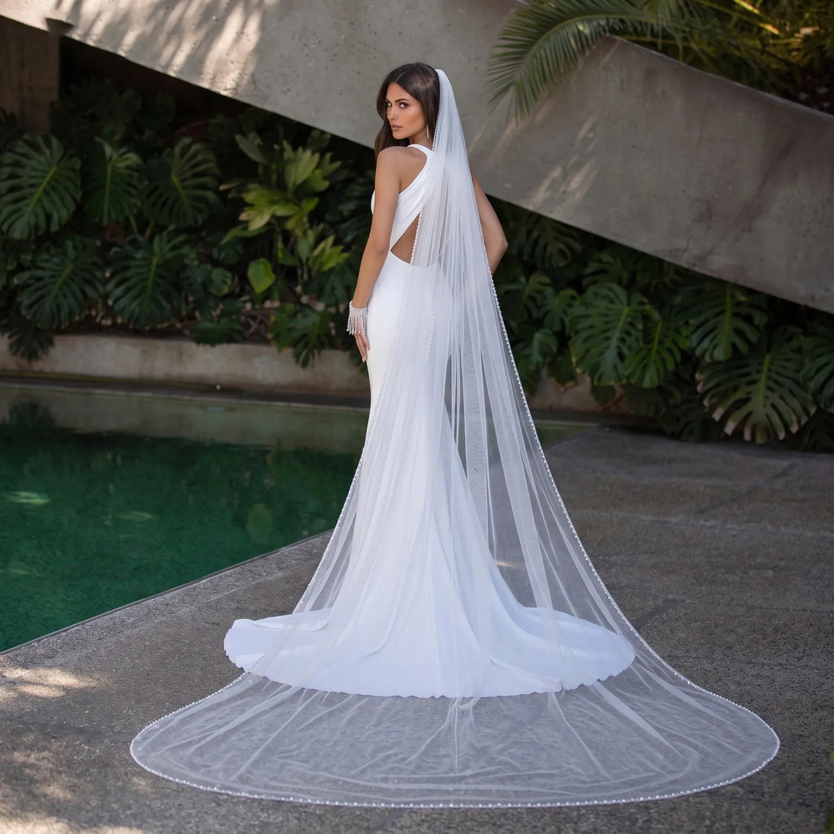 Rear view of bride in strapless lace gown wearing a 300cm single-tier veil with delicate pearl trim cascading into a wide-spread circular train