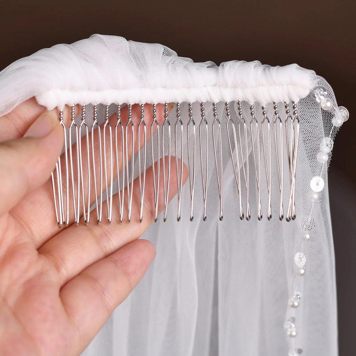 Macro photo of silver metal hair comb wrapped in soft white fabric, securely hand-stitched to the gathered tulle headpiece