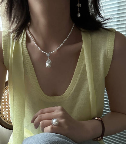 Close up detail of organic baroque pearl pendant and round cubic zirconia accent on seed pearl necklace
