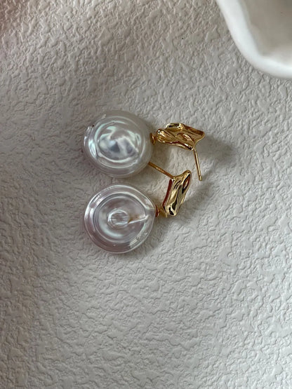 Roman Holiday coin baroque pearl drop earrings inside a ceramic shell dish with dried flowers.