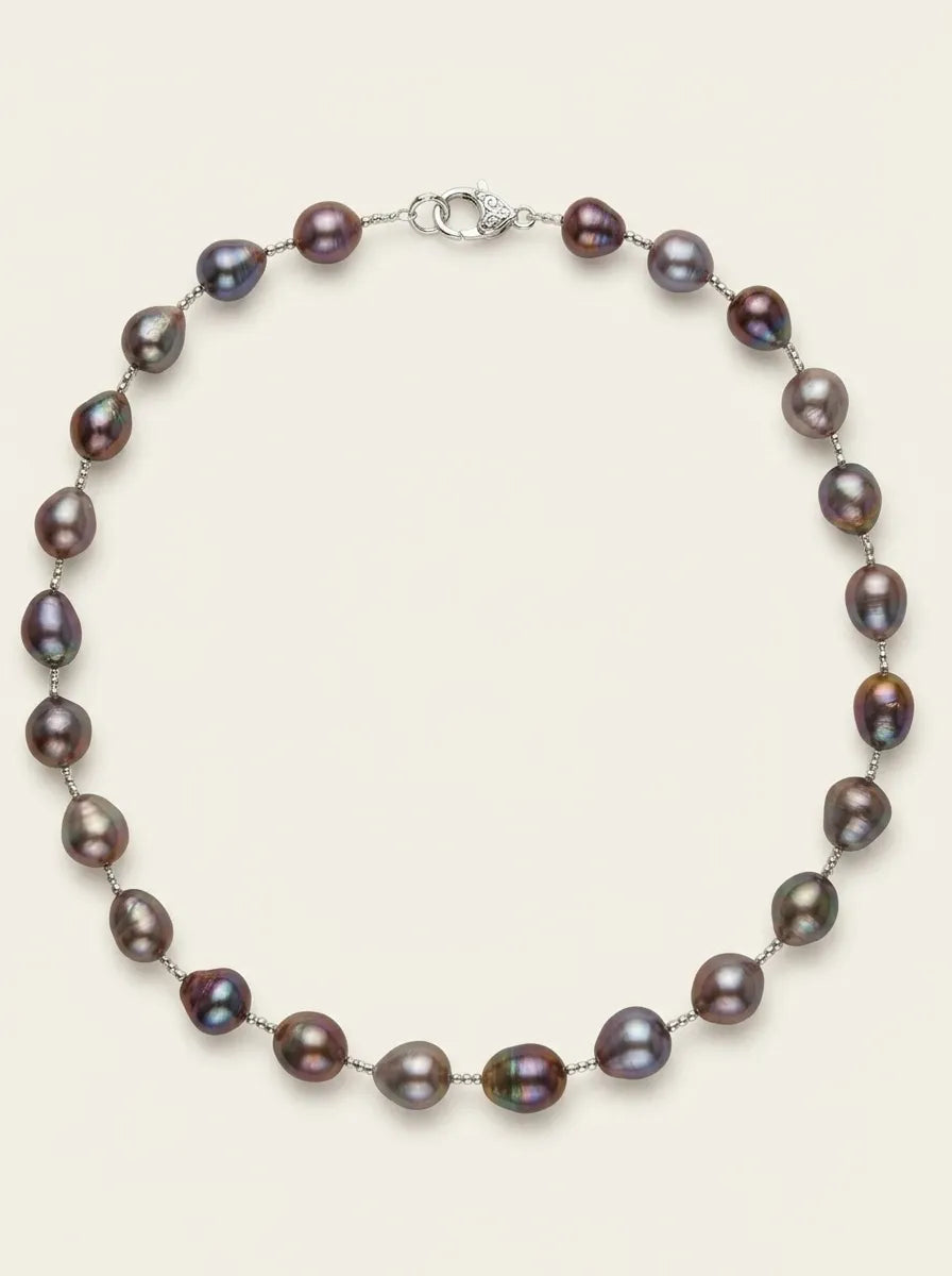 Flatlay view of deep purple baroque pearl strand necklace with S925 silver clasp on off-white background.