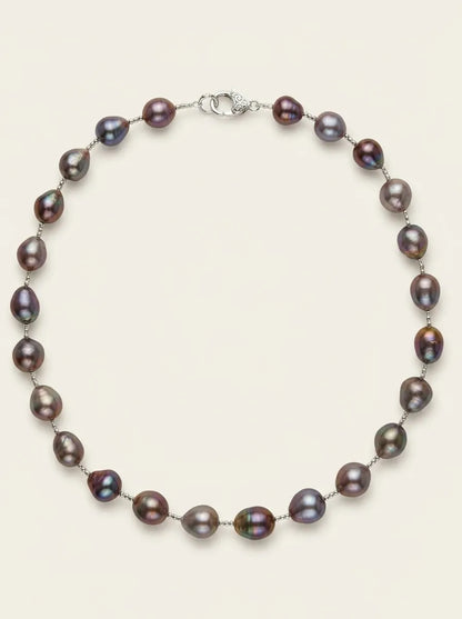 Flatlay view of deep purple baroque pearl strand necklace with S925 silver clasp on off-white background.
