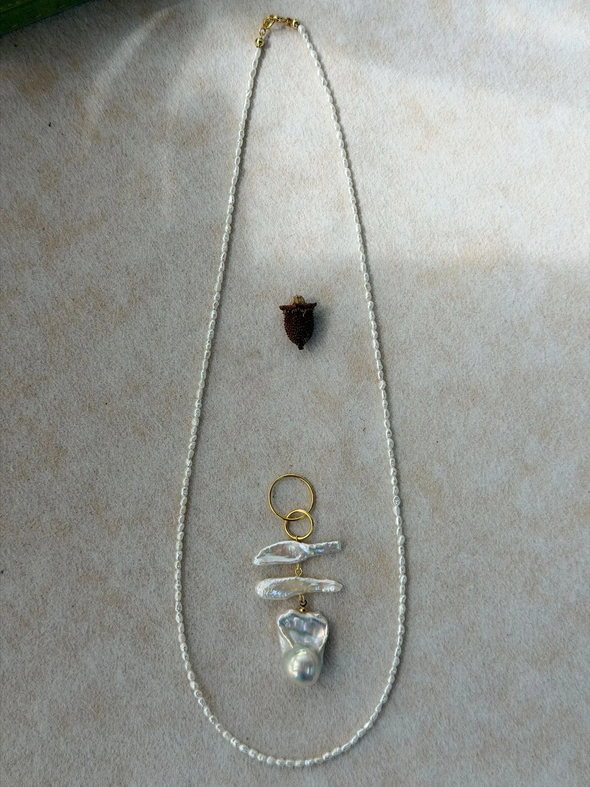 Detached freshwater seed pearl chain laid out with the separate baroque pearl pendant, showing the 2-in-1 convertible feature.