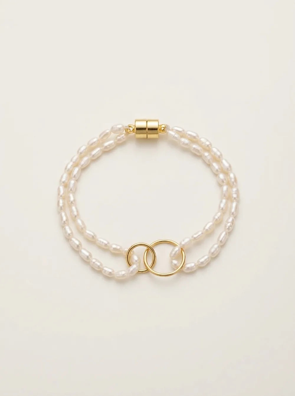 Flatlay view of the double-ring freshwater seed pearl layered bracelet with gold magnetic closure.