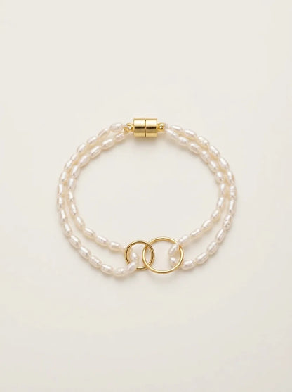 Flatlay view of the double-ring freshwater seed pearl layered bracelet with gold magnetic closure.