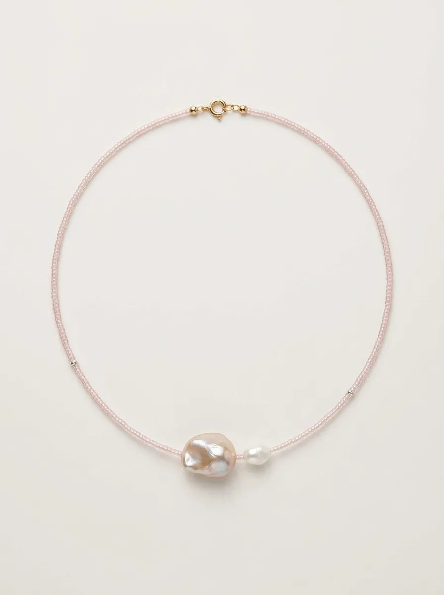 Full view flatlay of fairy pink beaded baroque pearl choker on light background.