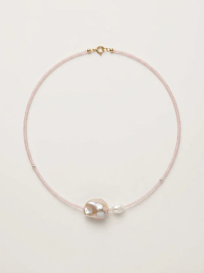 Full view flatlay of fairy pink beaded baroque pearl choker on light background.