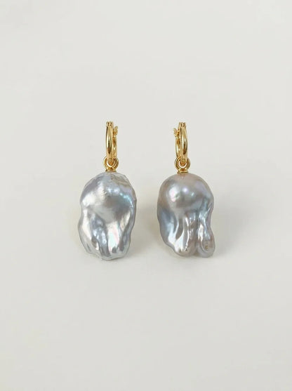 Pair of 18k gold-plated S925 sterling silver flame-tailed baroque pearl huggie hoop earrings flatlay.