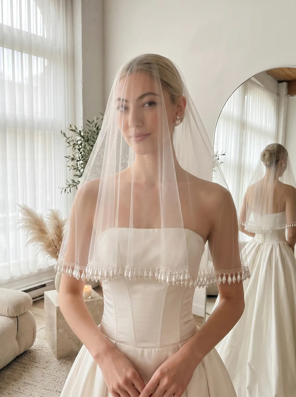 Bride wearing a comb-free French drop veil with dangling teardrop pearl tassel trim draped as a front blusher