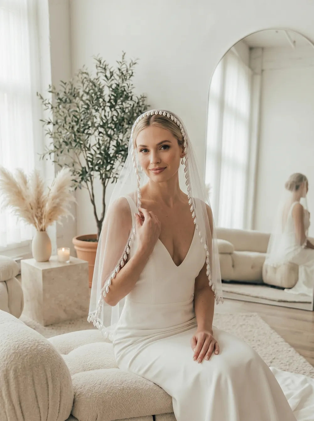 Bride wearing a pearl fringe drop veil seated in natural indoor lighting showing elegant drape