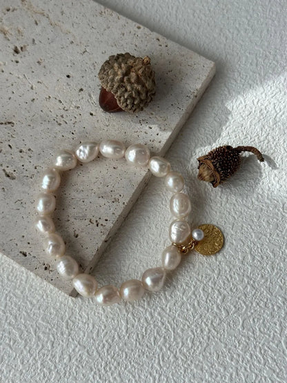 Gardener pearl elastic bracelet arranged on travertine stone slab with acorn photo props.