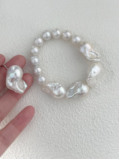 Hand holding the large baroque freshwater pearl beaded elastic bracelet demonstrating scale and luster.