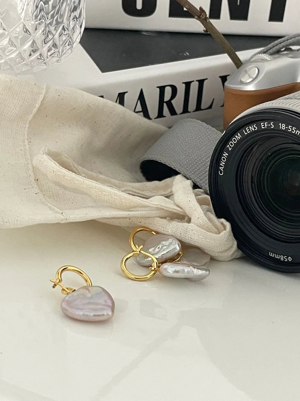 Large heart baroque pearl drop earrings displayed next to a vintage camera prop.