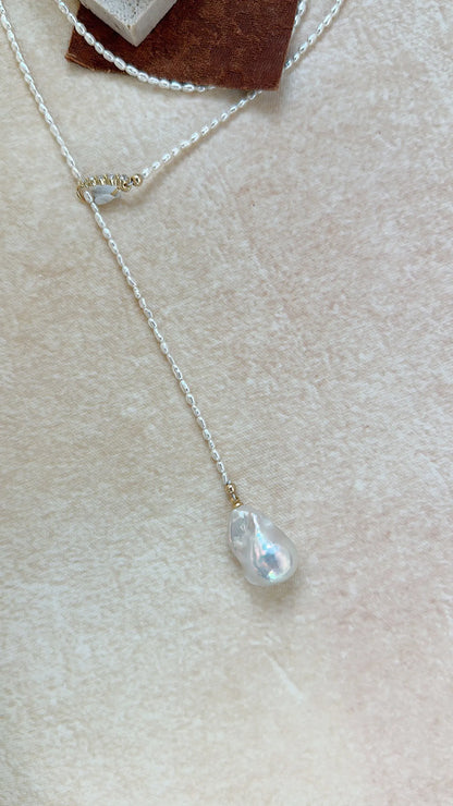 Flatlay of the Keshi pearl Y-lariat necklace with gold CZ slider clasp on neutral fabric.