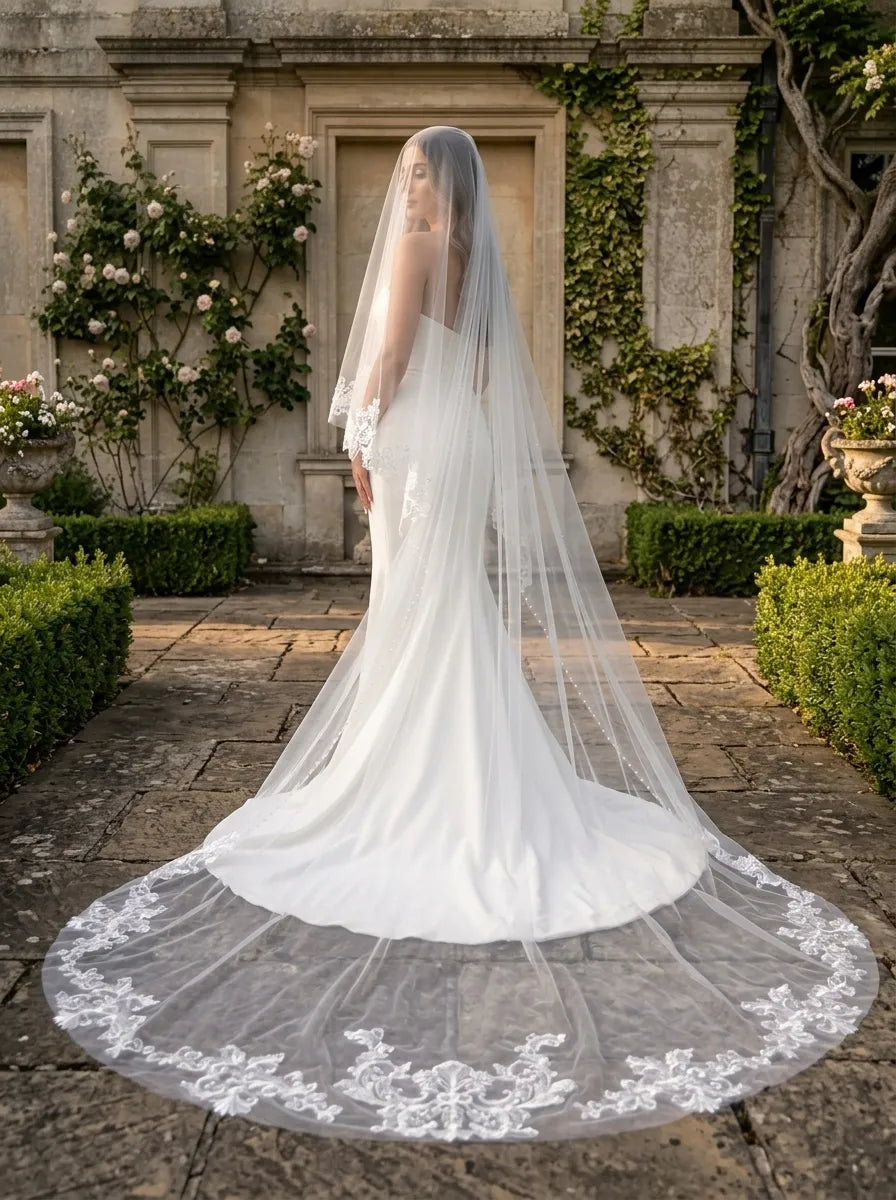 Rear view of bride in strapless gown with 300cm lace appliqué and pearl trimmed cathedral veil in garden