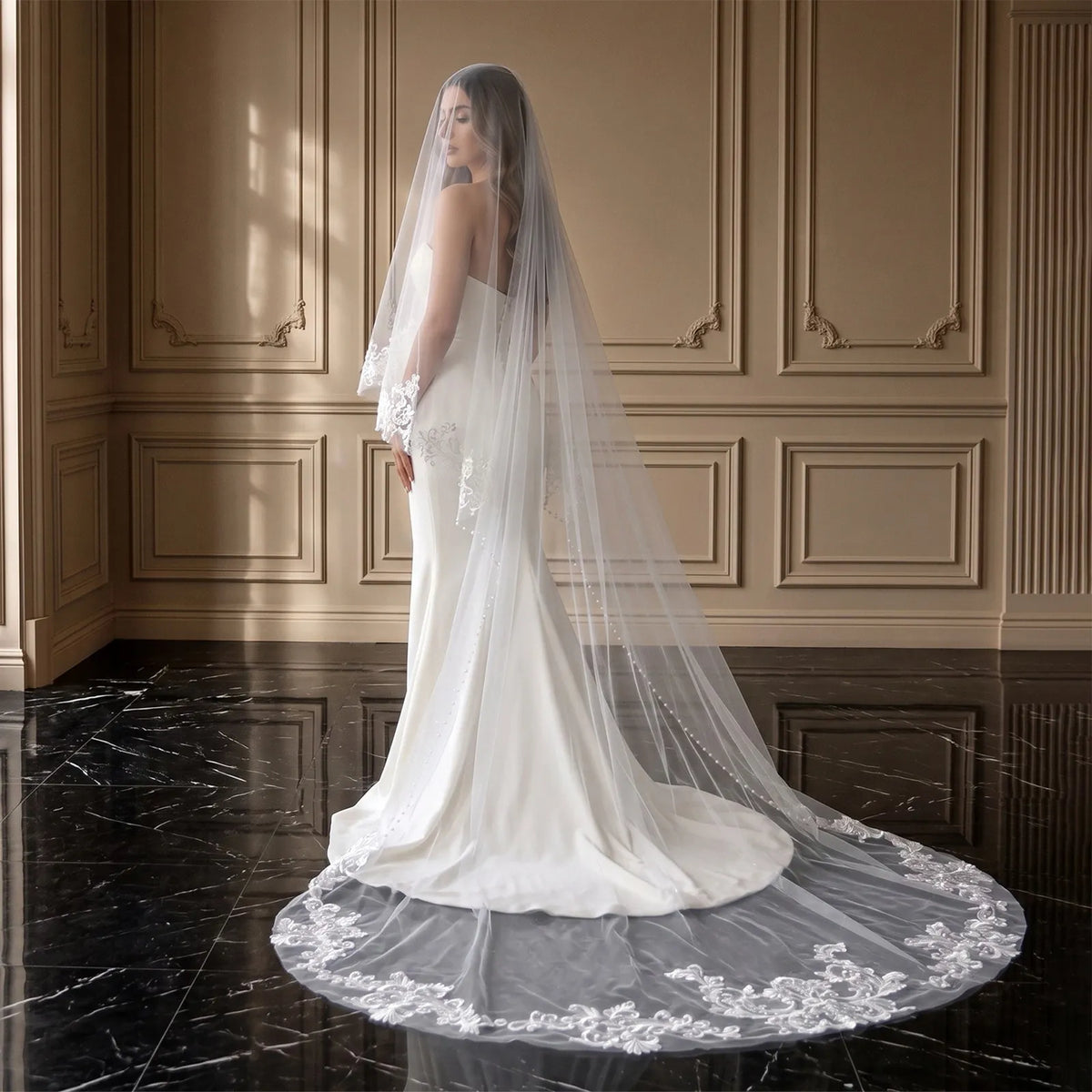 Full rear view of bride wearing 300cm drop veil with lace appliqué trailing train on dark tile floor