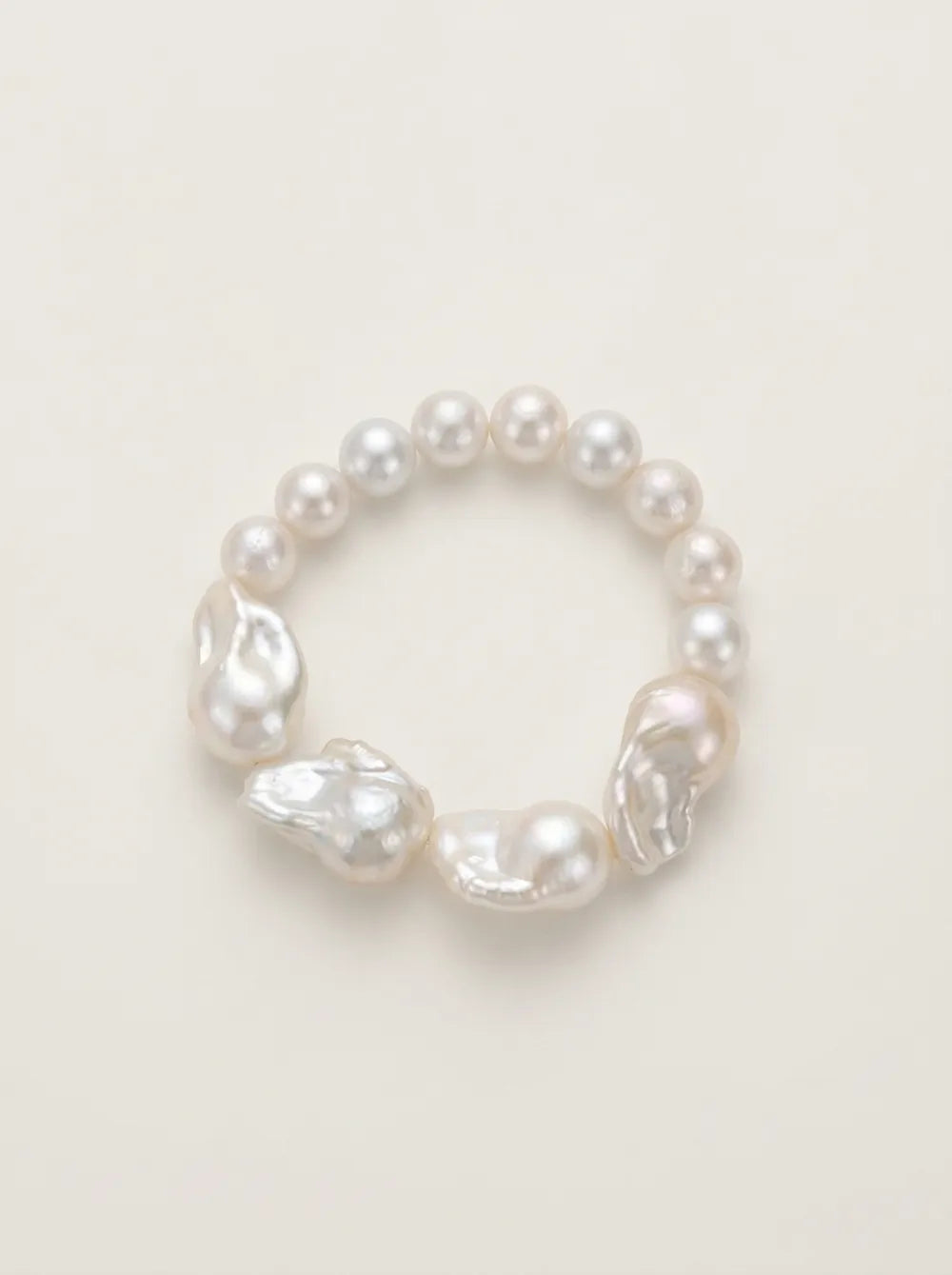 Flatlay view of the circular large baroque pearl beaded elastic bracelet with iridescent luster.